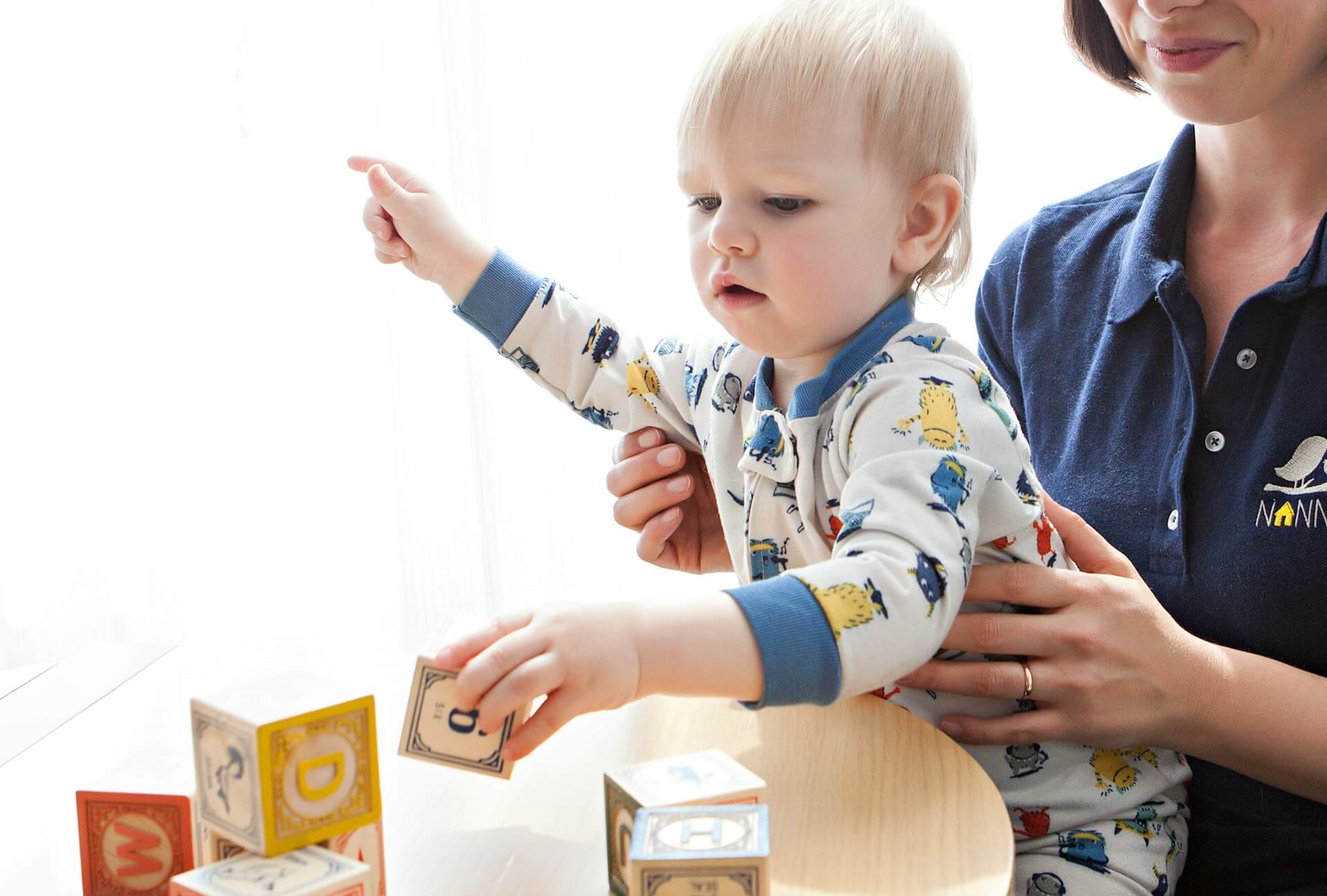 Children and an educator building with alphabet blocks